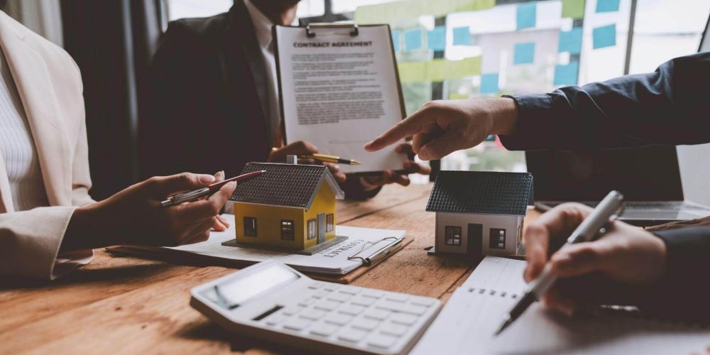 a group of people sitting around a wooden table reviewing legal documents
