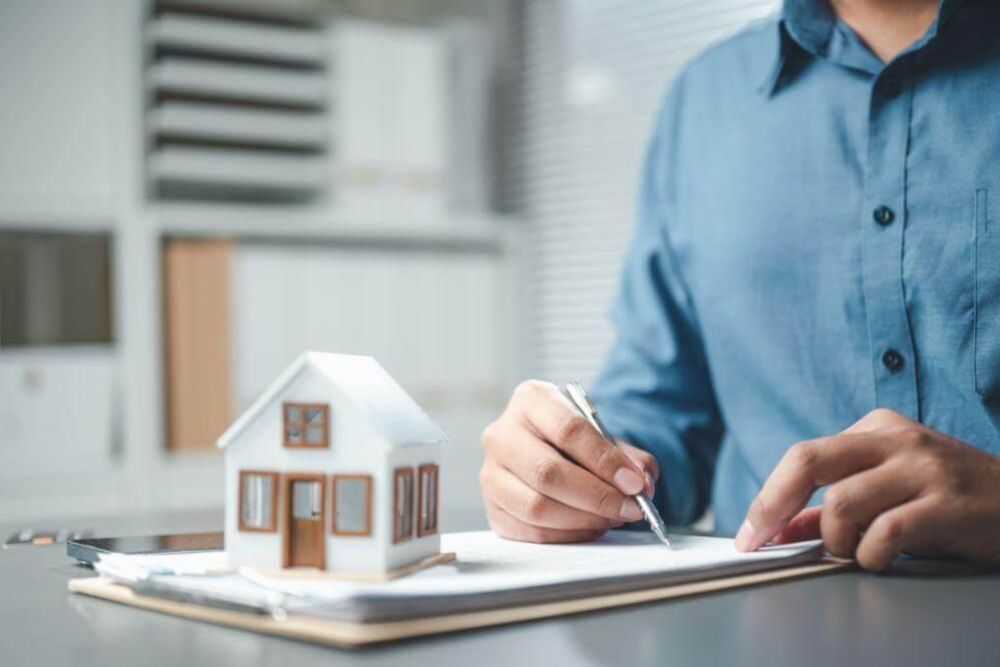 a man writing on a notepad with a model of a house