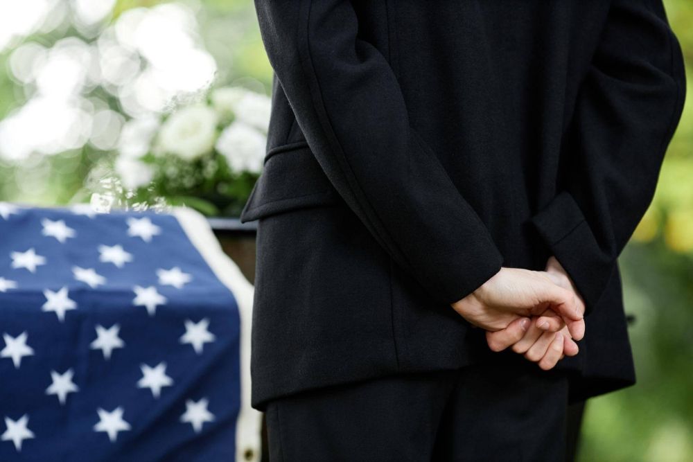 a man in a suit standing next to a flag