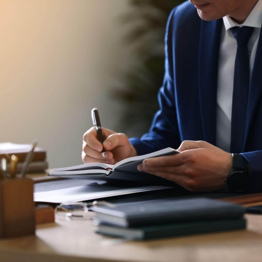 a man sitting at a desk writing on a piece of paper