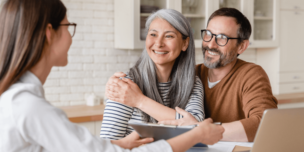 a couple of people sitting at a table with a laptop and talking to a lawyer