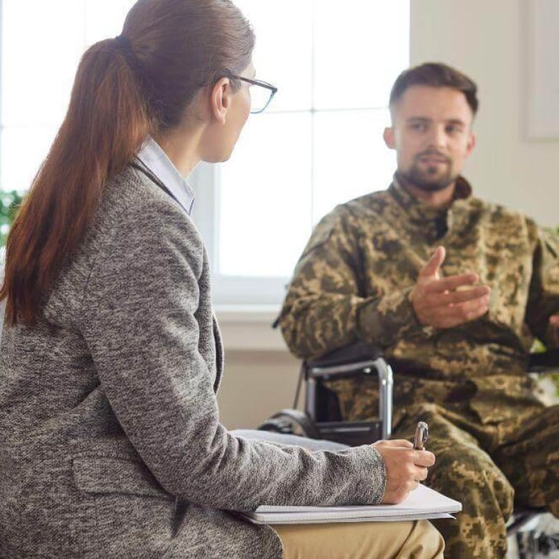 Woman in a wheelchair talking to a soldier about