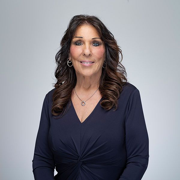 Elizabeth Stevenson with long dark hair and a navy blouse smiling against a light gray background.