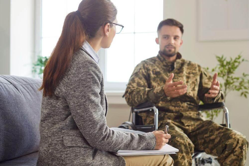 Woman in a wheelchair talking to a soldier about