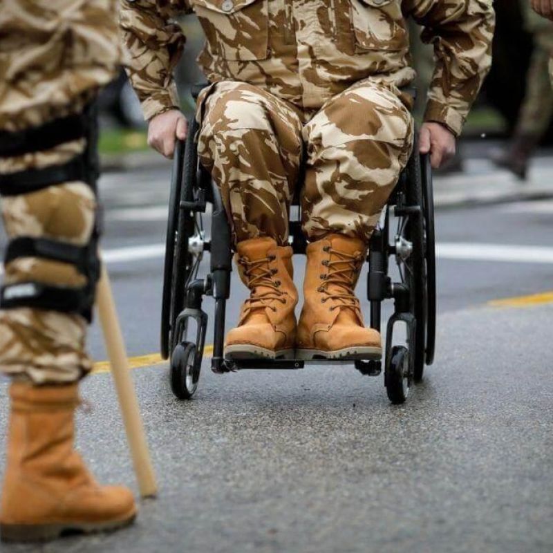 Veteran in a wheelchair led by soldiers