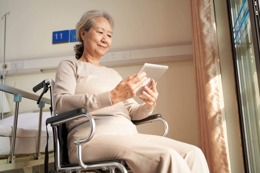 an elderly woman sitting in a chair holding a tablet