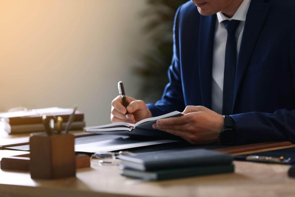 a man sitting at a desk writing on a piece of paper