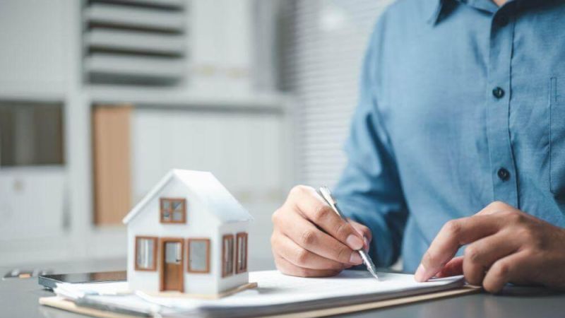 a man writing on a notepad with a model of a house