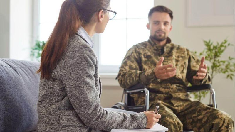 Woman in a wheelchair talking to a soldier about