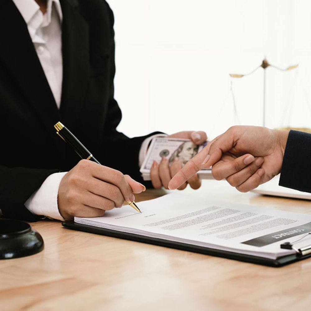 Legal contract signing with gavel and scales of justice on desk, symbolizing law and legal agreements.