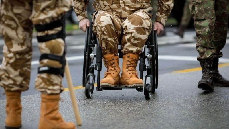 Veteran in a wheelchair led by soldiers
