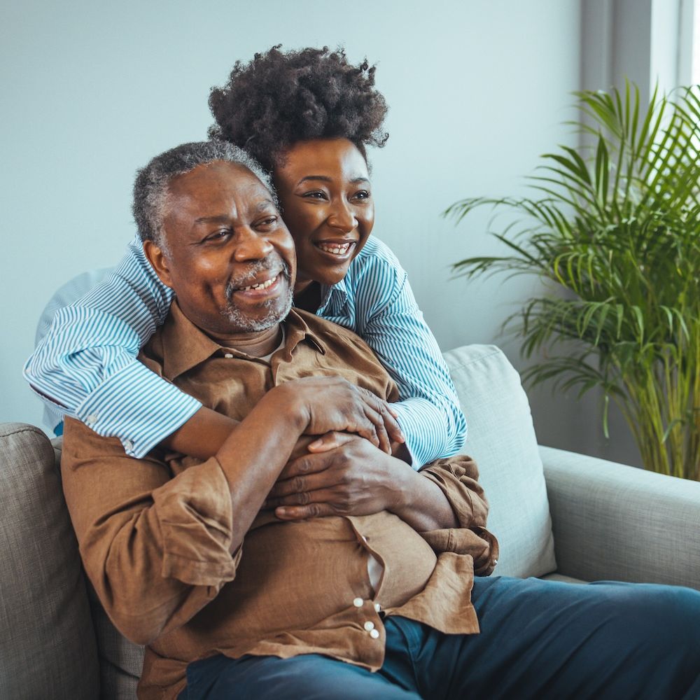 Father and daughter hugging on a cozy sofa, smiling and enjoying quality time together at home.