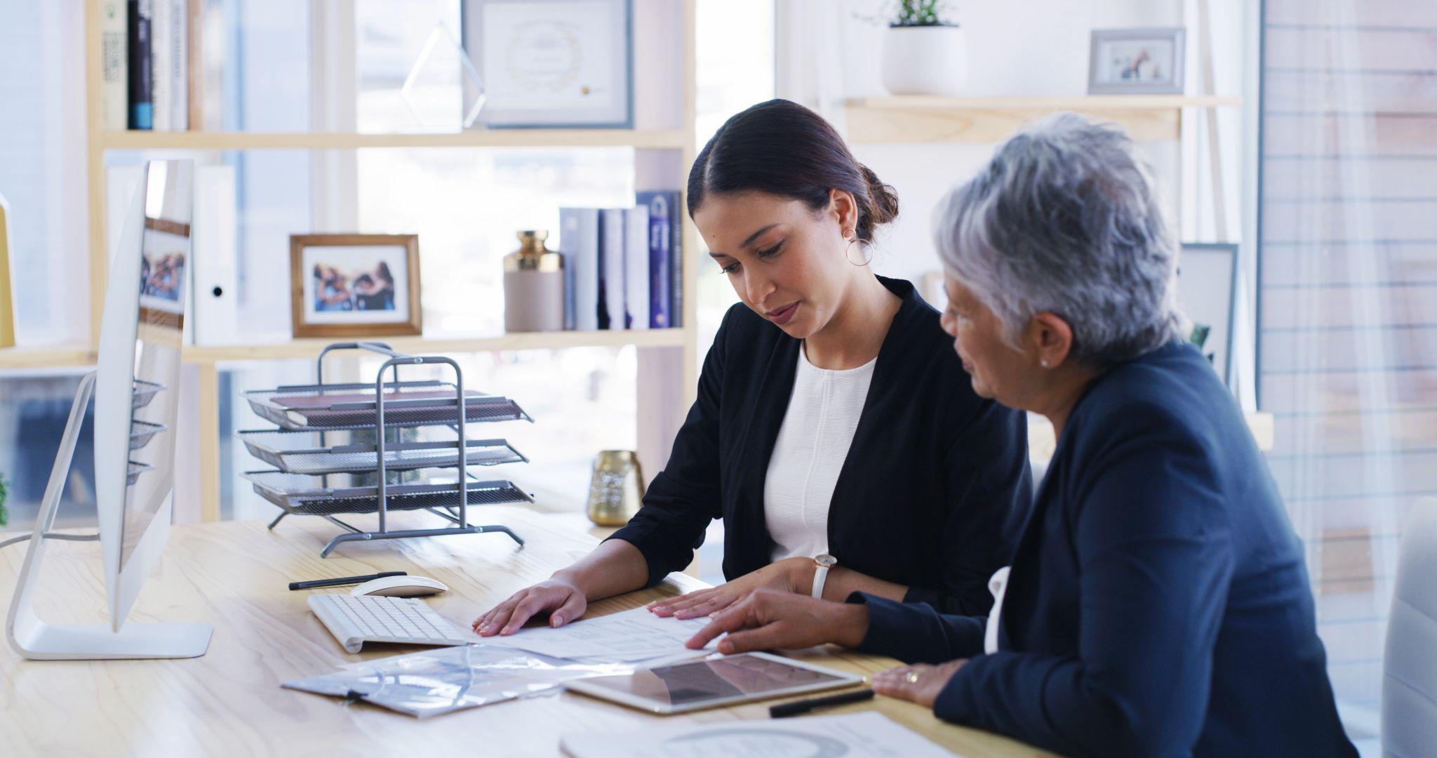 an elderly woman reviewing documents with a lawyer in an office