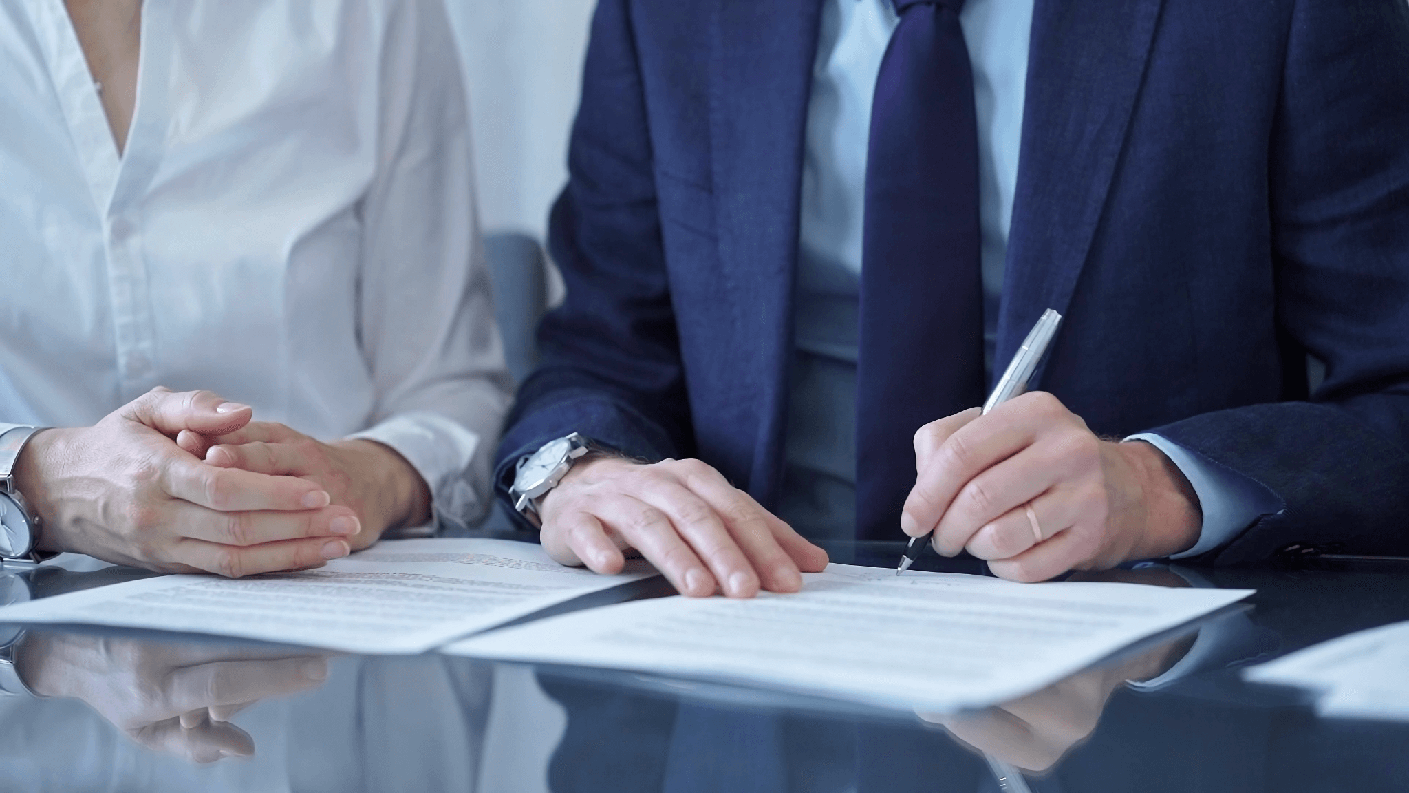 a couple of people sitting at a table signing papers