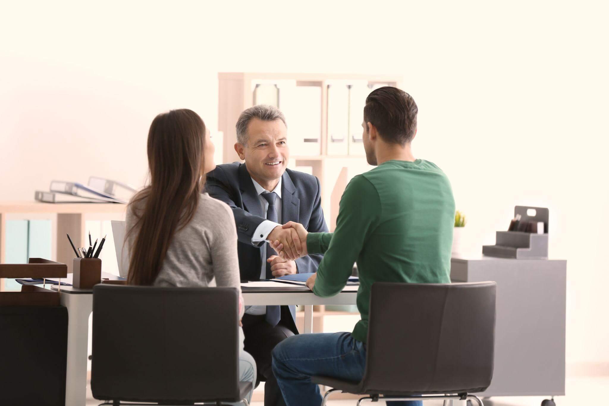 a group of people sitting around a table shaking hands