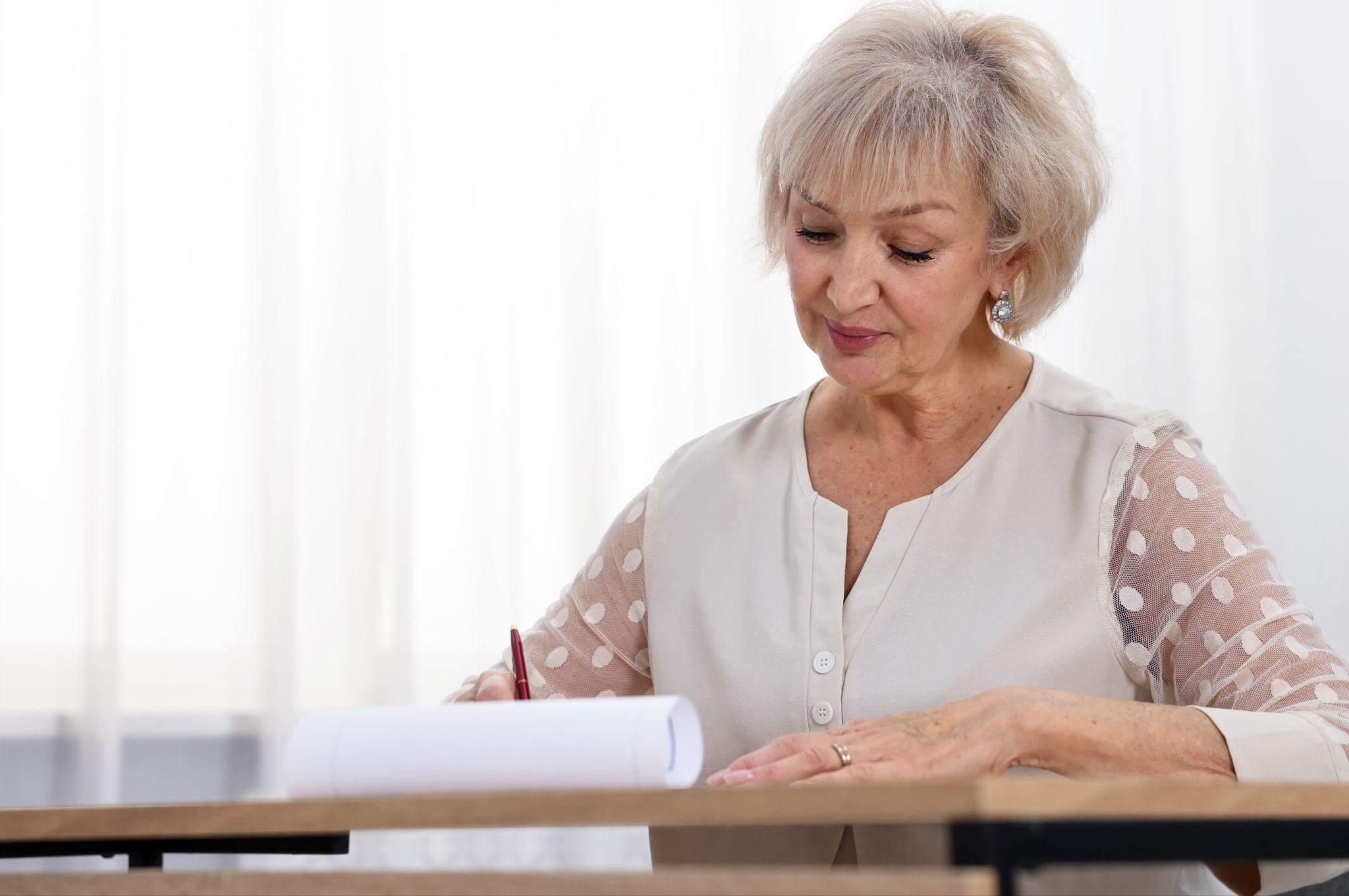 a woman sitting at a desk writing on a piece of paper