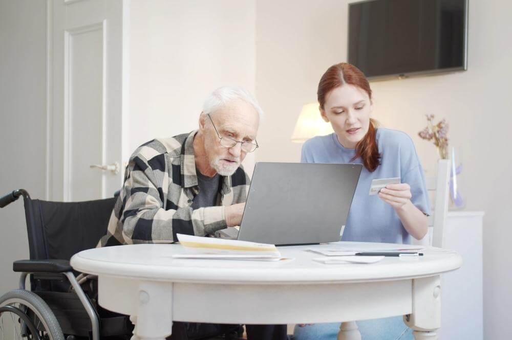a man in a wheelchair and a woman looking at a laptop