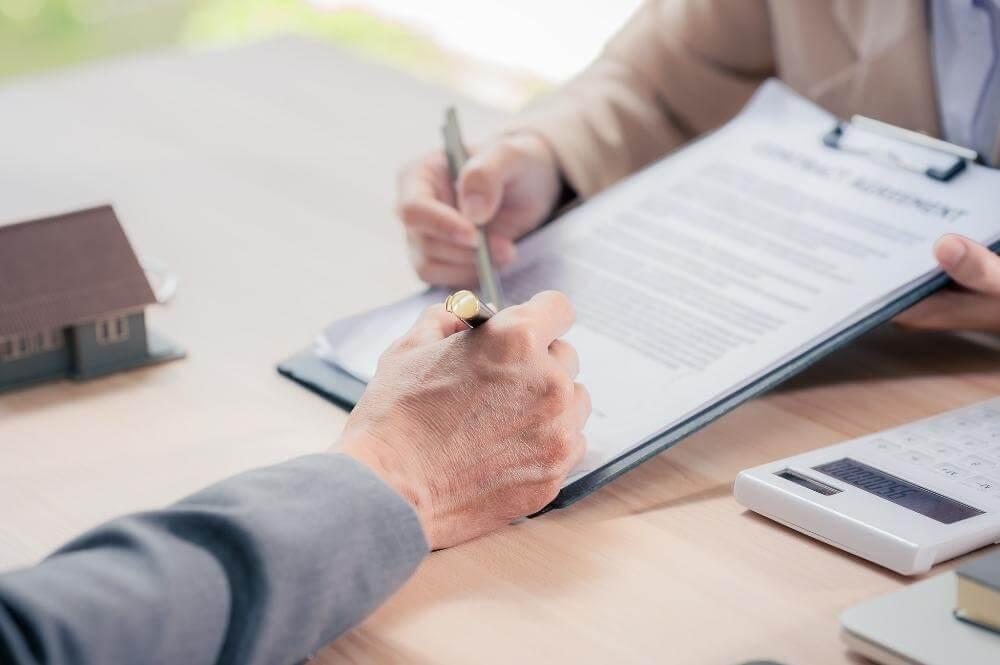 two people sitting at a table signing a document