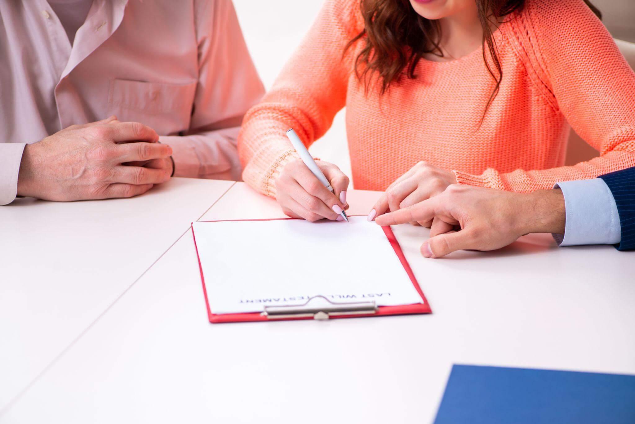 Man and woman signing probate papers at a table
