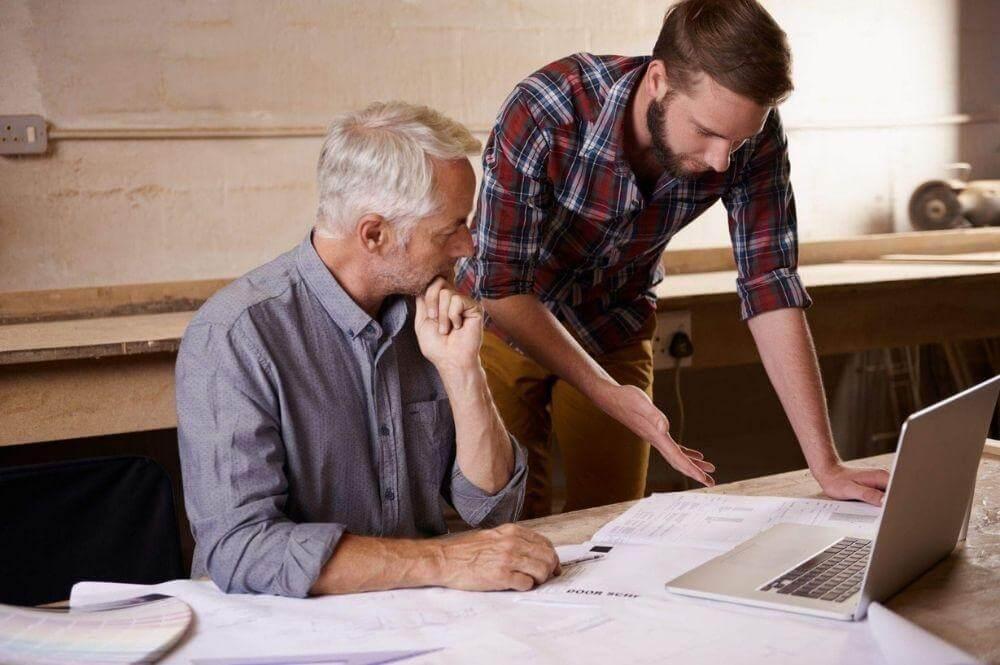 Two men reviewing client information on a laptop for